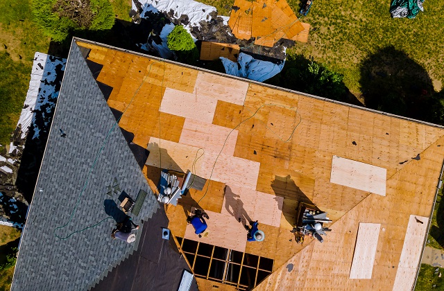 Roof construction repairman on a residential apartment with new roof shingle being applied